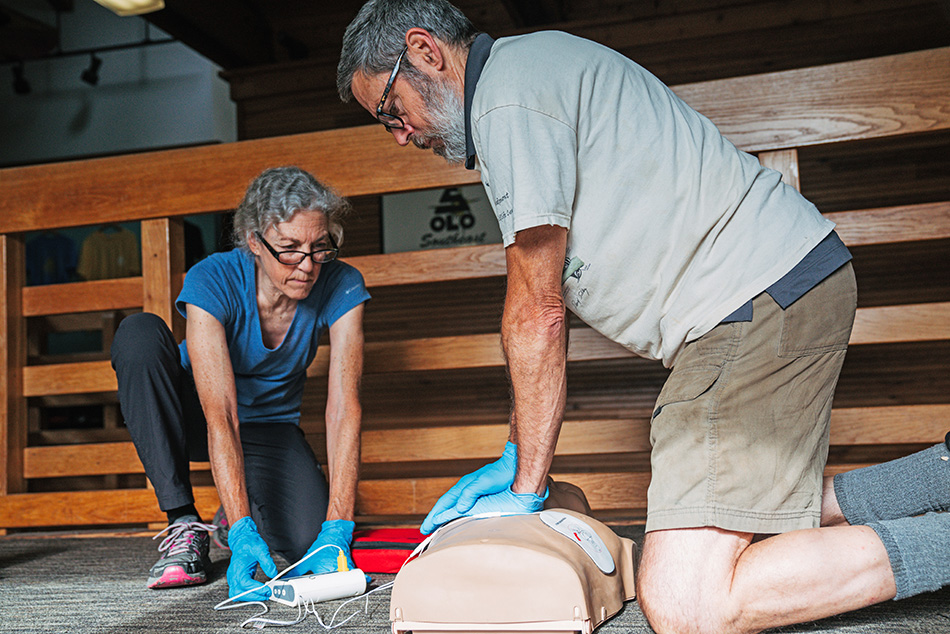 A lady and a man practicing using an AED on a dummy for their certification.